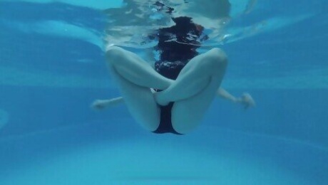 Girl in one-piece swimsuit swimming and doing yoga in public pool